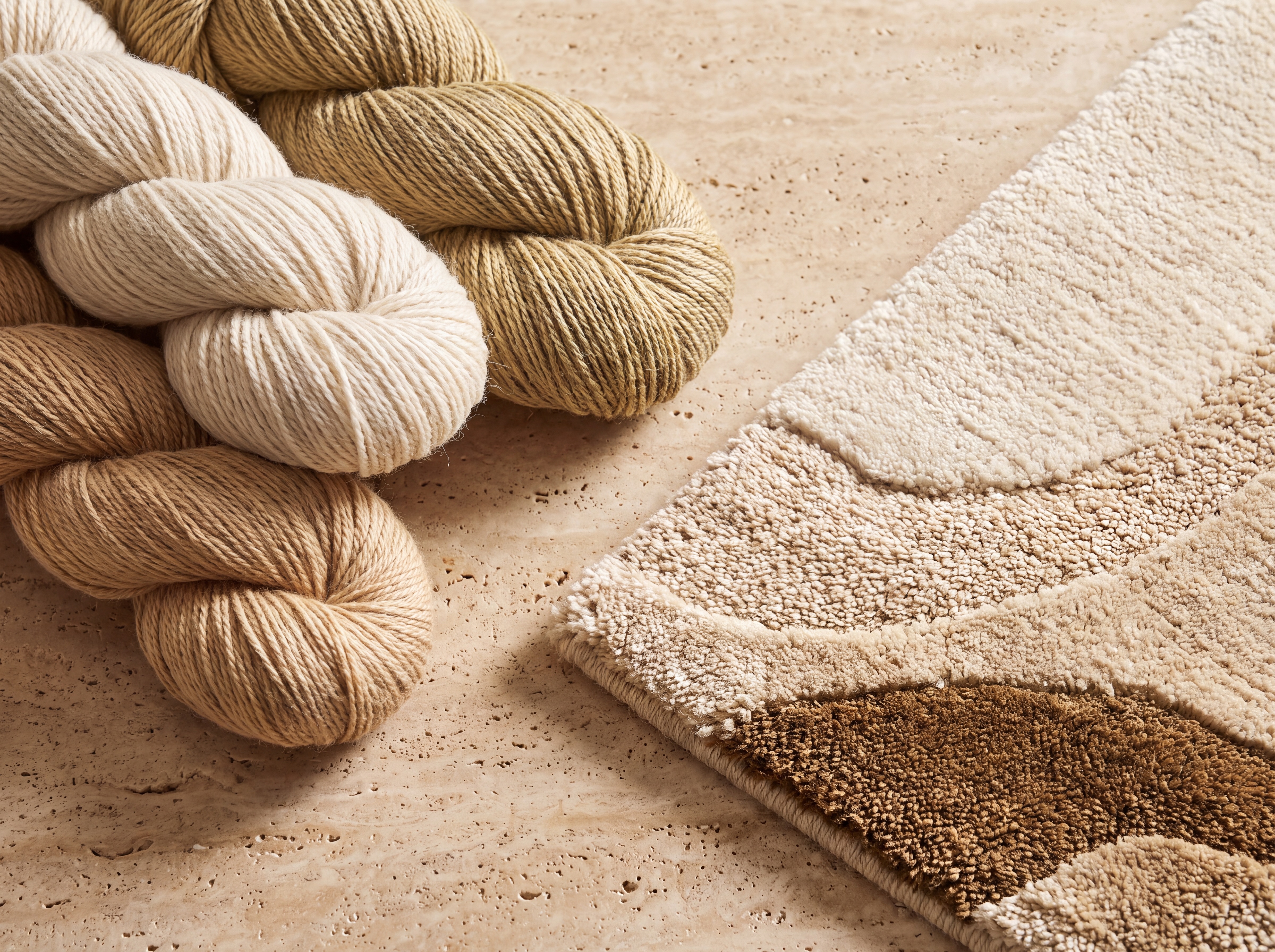 Raw hanks of hand-spun Himalayan wool and natural silk beside a modern hand-knotted rug